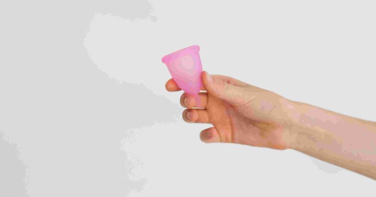 compressed side view hand holding reusable menstrual product