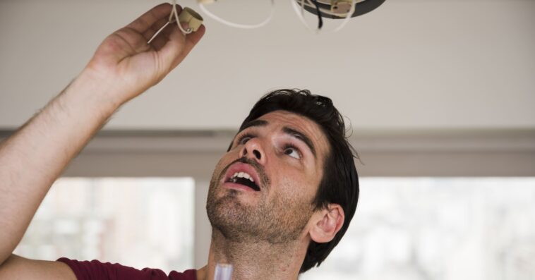 close up male electrician installing holder ceiling light 1
