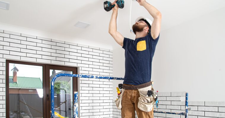 electrician builder work installation lamps height professional overalls with drill repair site 1