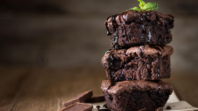 A stack of 3 perfect chocolate brownie pieces with a mint leaf on it