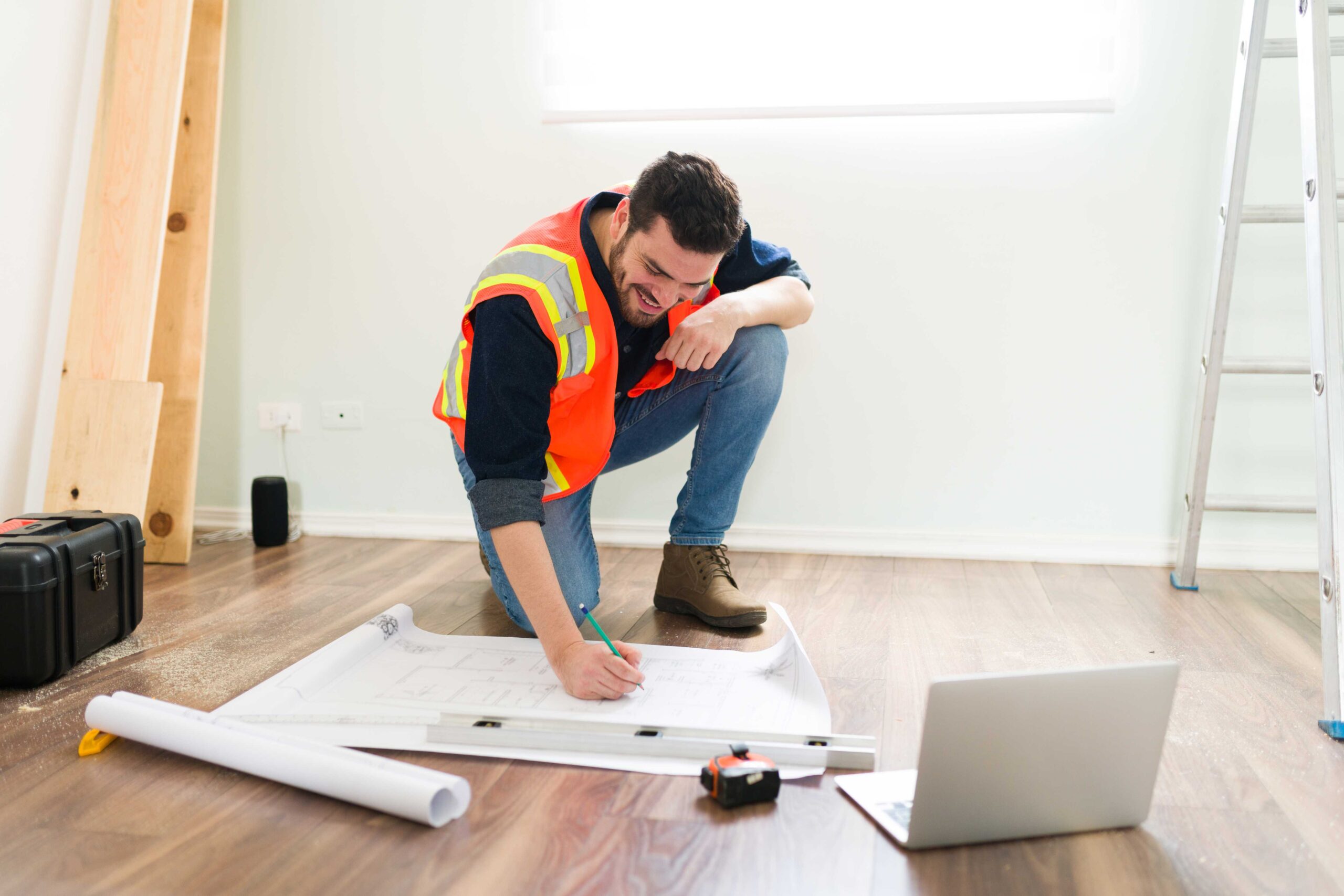Trusted House Renovation Contractor in London 1 cheerful latin architect smiling while looking online information laptop working construction plans 1 scaled