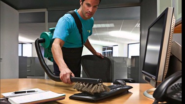 Professional cleaner vacuuming office desk and keyboard – office clean out services Kent WA