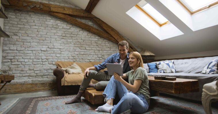 young couple using tablet sitting floor home 1 1