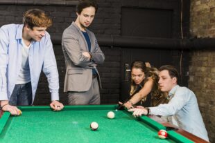 male friends looking woman playing snooker club