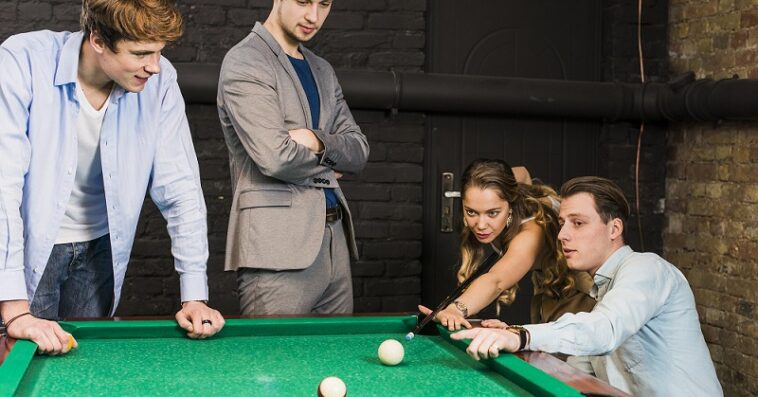 male friends looking woman playing snooker club